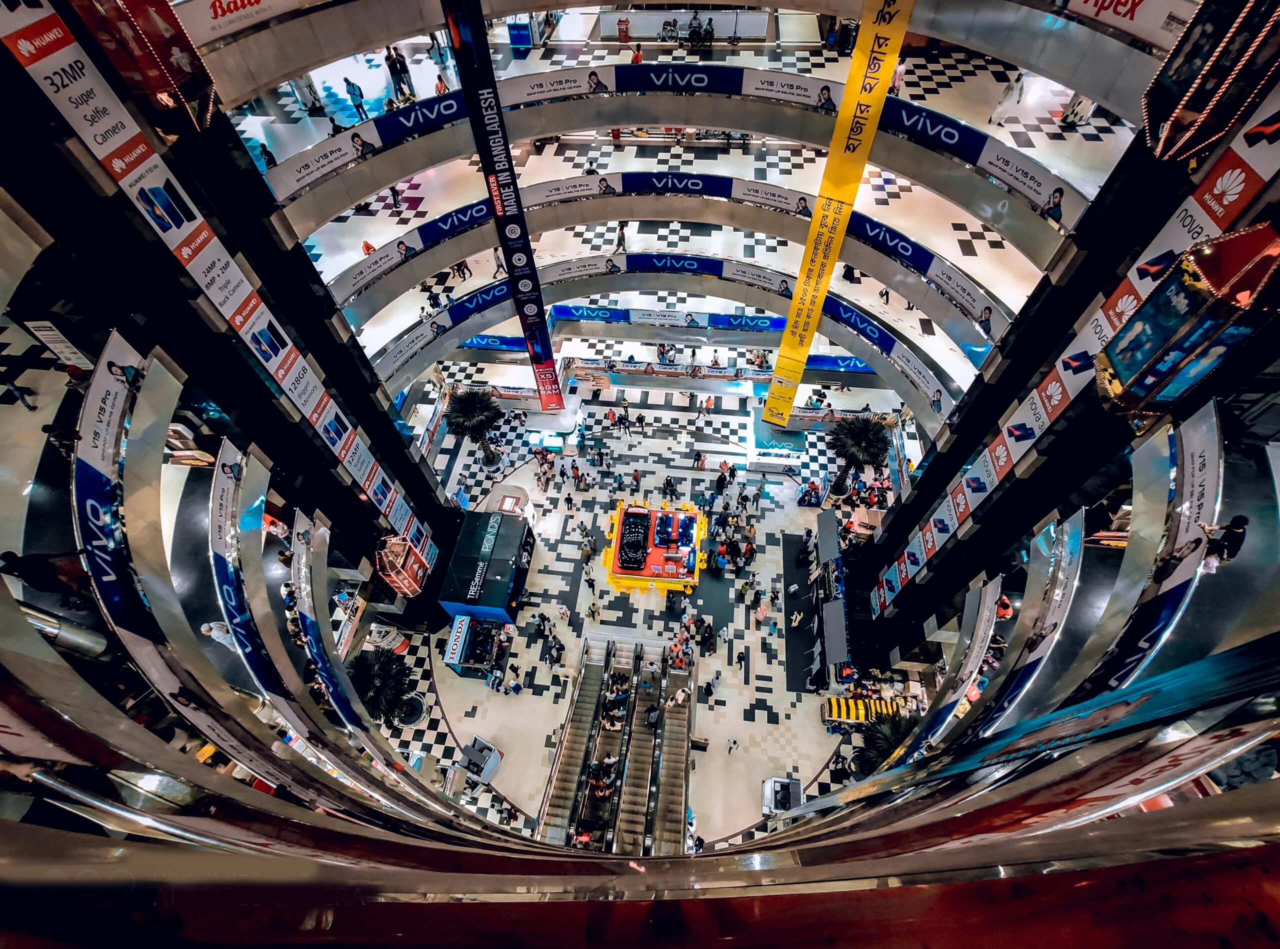 A bustling multi-story indoor shopping mall in Dhaka, Bangladesh viewed from above.